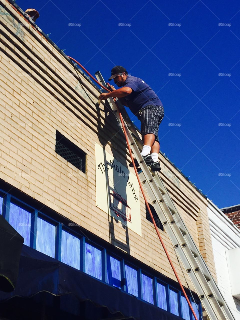 Painter on ladder against a small town business with blue sky's 