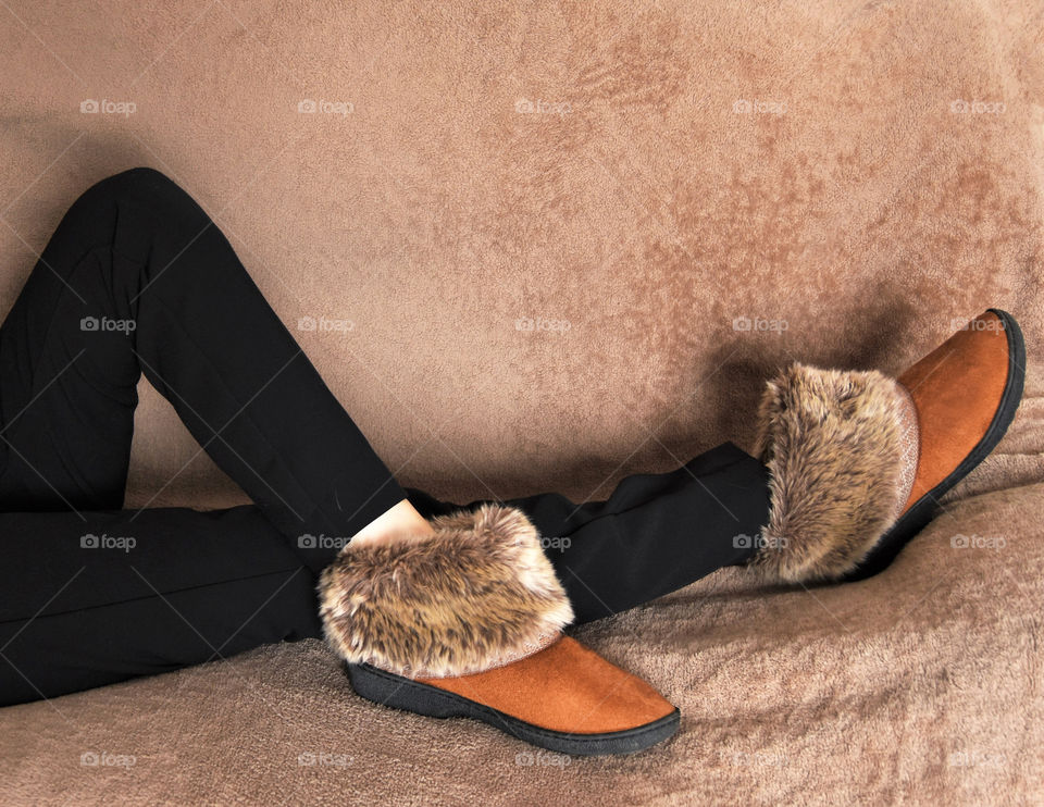 Warm fuzzy slippers worn by a lady relaxing on a couch 