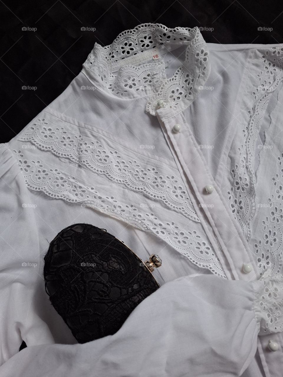 vintage white lace shirt with retro handbag on black background