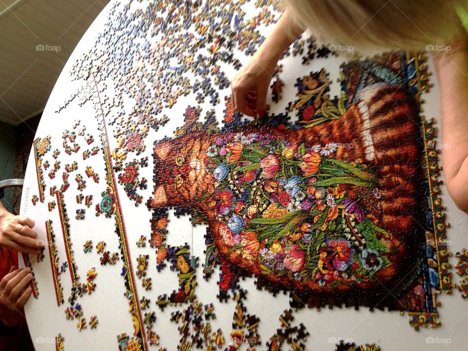 Friend’s putting together a jigsaw puzzle as seen from above.