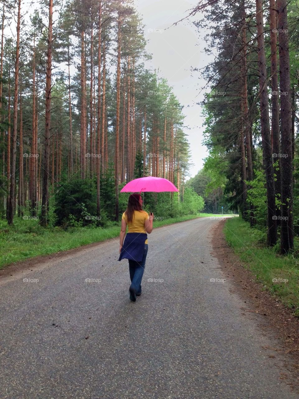 Woman walking in the woods with pink umbrella 