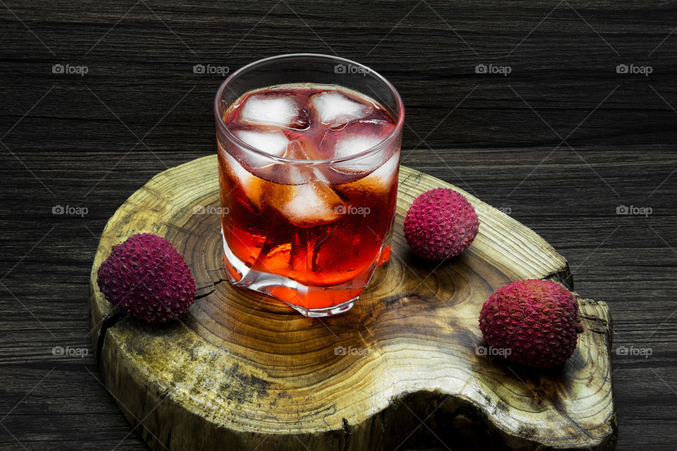 Red cocktail with Ice cube on tree stump