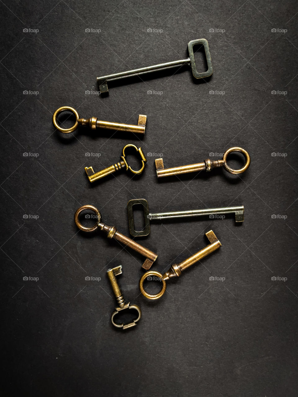 Flatlay of various black, brass, and gold cabinet keys on a black background. 