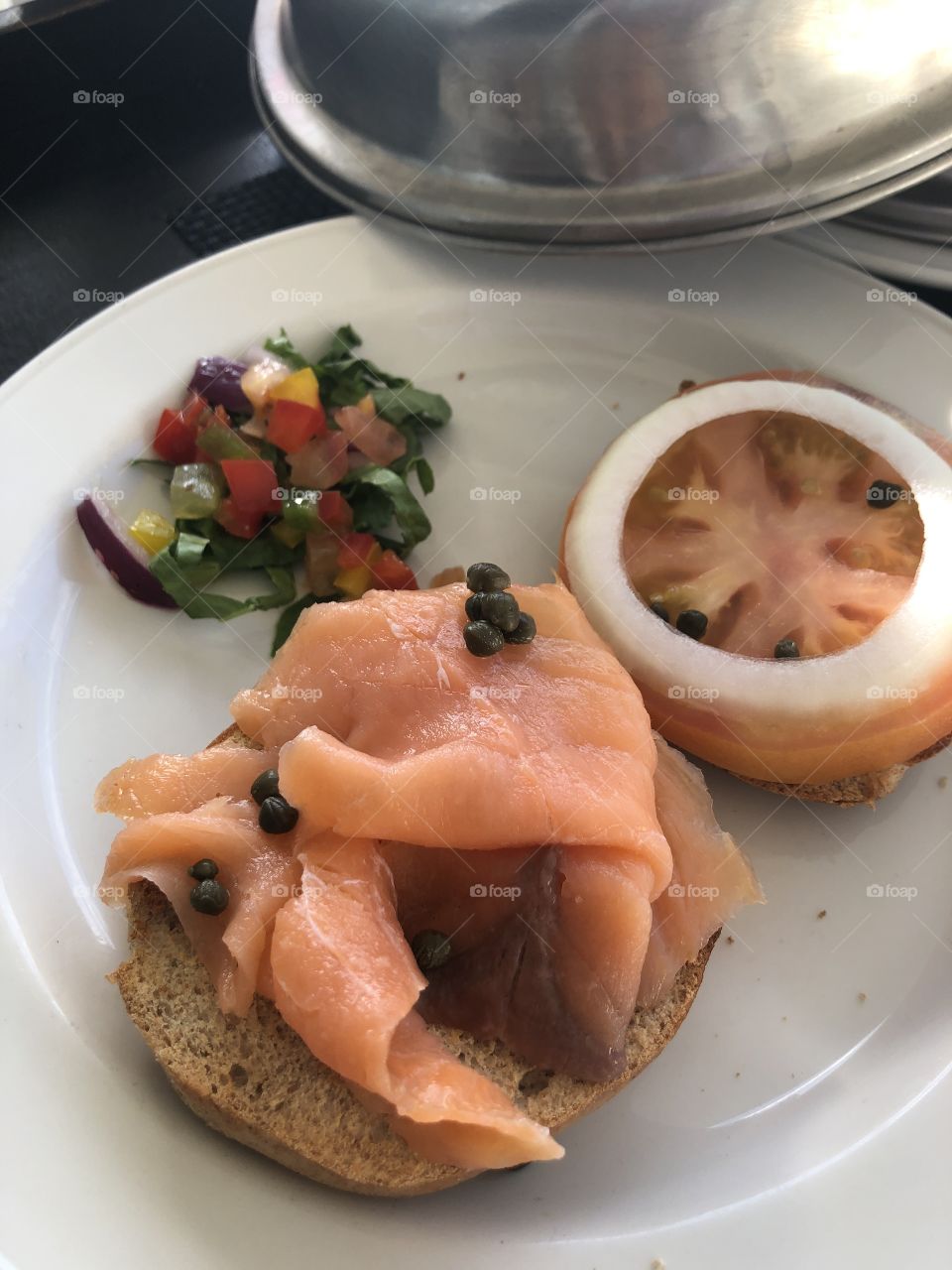 Smoked salmon over a bagel with tomatoes and onion plate 
