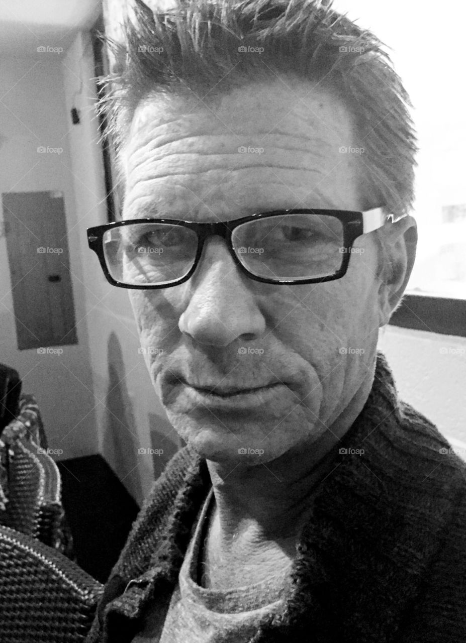 Close up photo in black-and-white of a man wearing glasses.