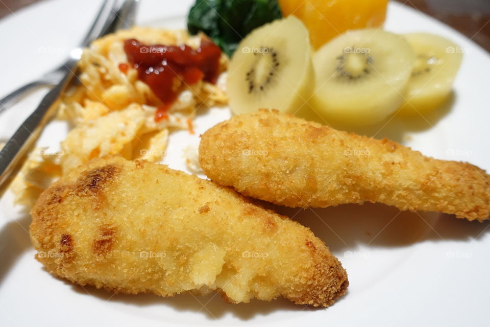 Balanced meal on one plate (Chicken cutlets, scrambled eggs, fruit and vegetables).