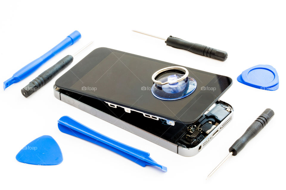 A damaged mobile phone with the tools needed to repair it on an isolated white background 