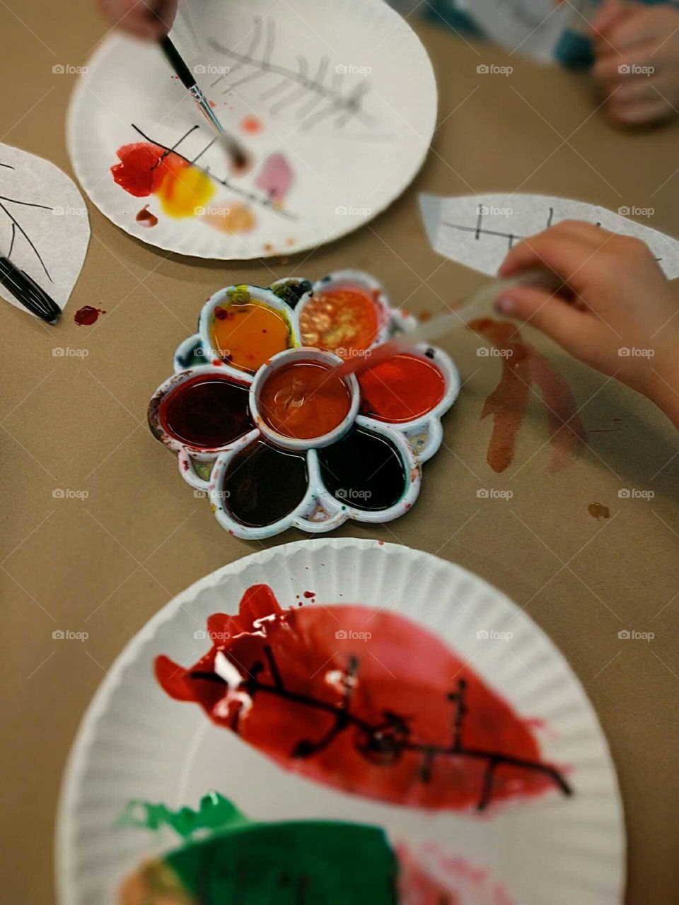 Two young children paint autumn leaves.