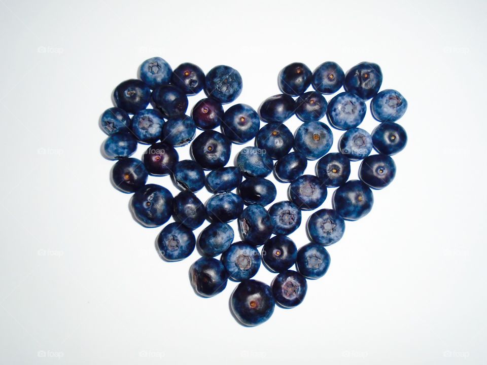Heart shape made of blueberries on white background