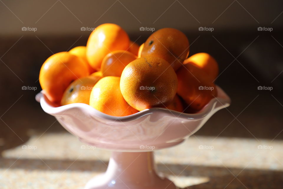 Bowl with oranges illuminated by early morning sunshine 