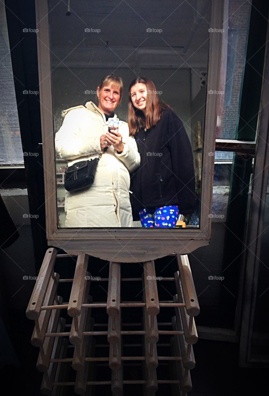 Mother and daughter taking selfie through mirror