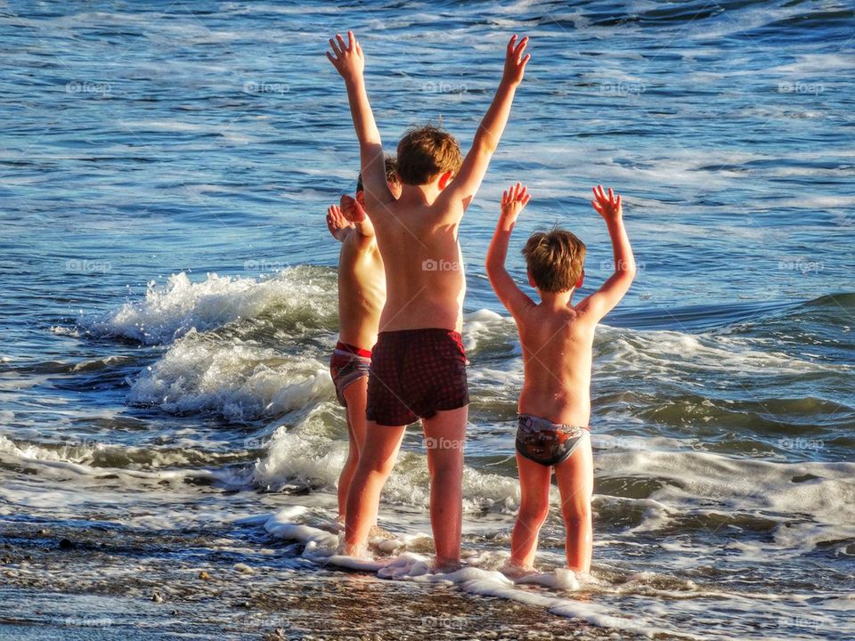 Young Brothers Raising Their Hands To The Sea