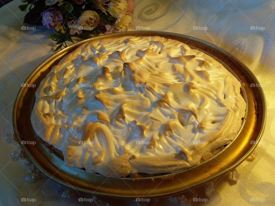 delicious pineapple meringue tart lightly golden top flowers behind