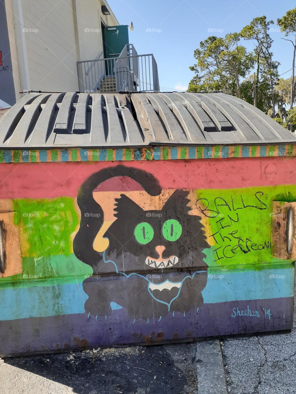 A colorful street art mural painting on a dumpster of a black cat in downtown Orlando.