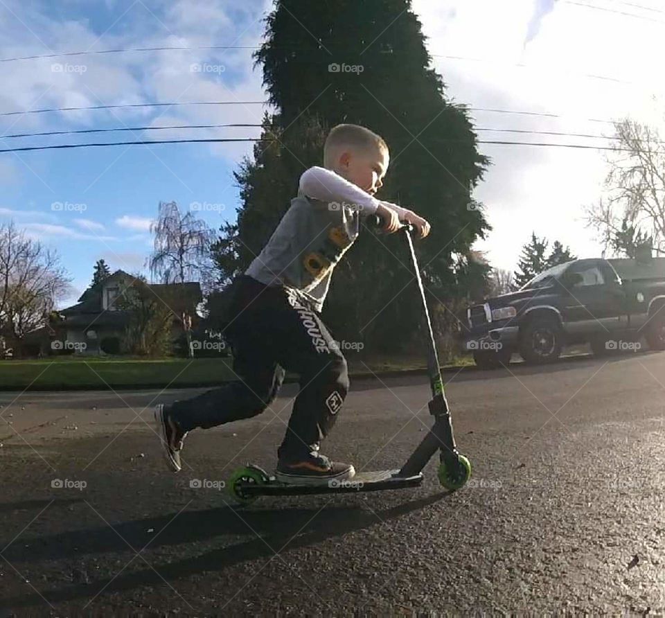 boy scooting down the street