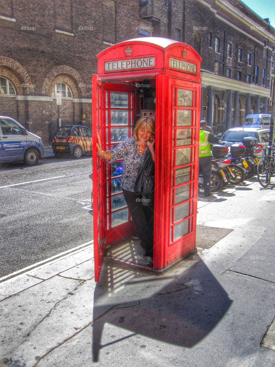 Mature woman speaking on mobile phone in telephone booth