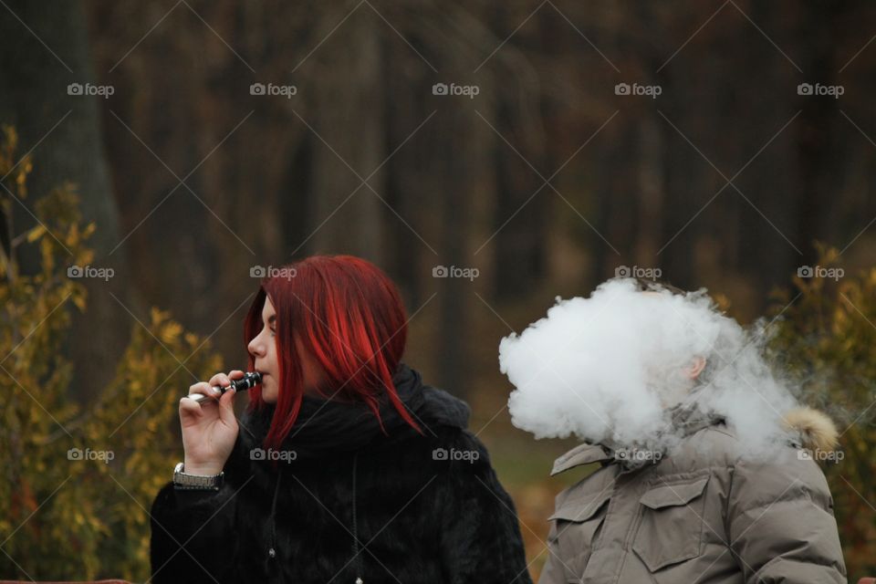Funny photo with a red-haired girl and a guy with a vape