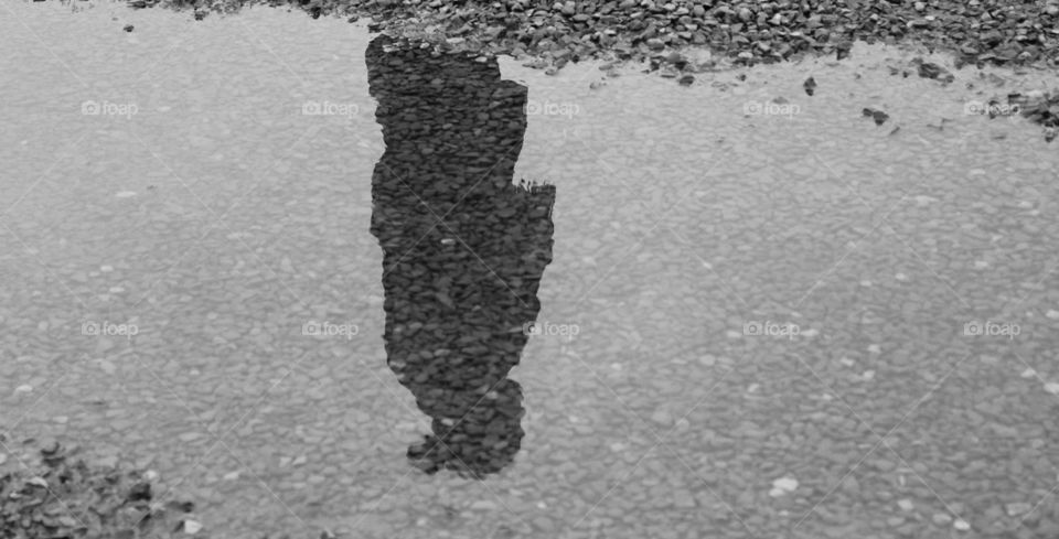 Reflection of woman on water puddle on Rocky surface