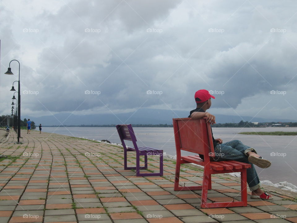 A boy on red chair side of the river
