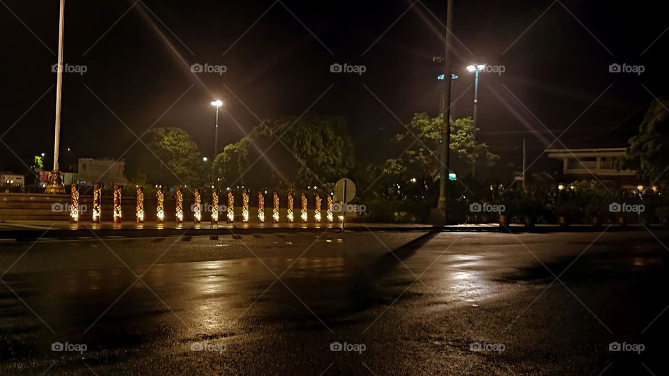 Night photo showing a wet highway with street lights and guard rails illuminated with decorative lights, creating a calm and peaceful atmosphere