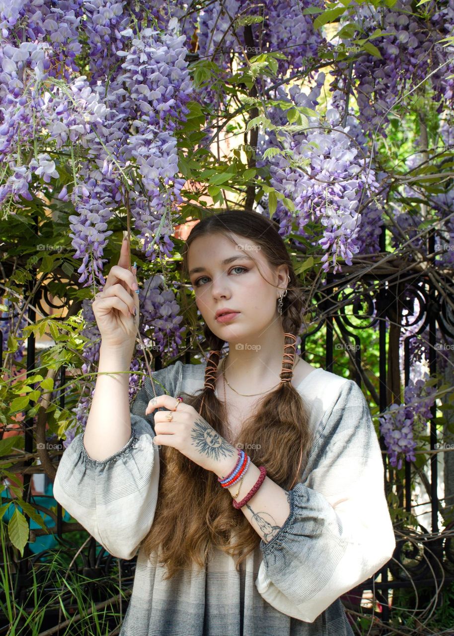Portrait of Young Girl on Background of Purple Flowers
