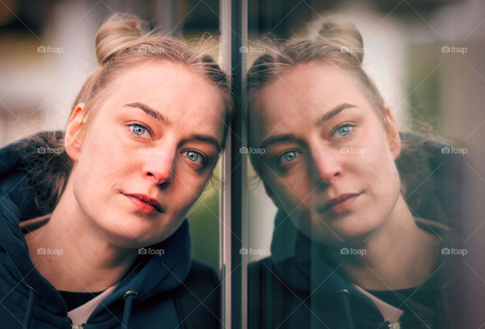 Portrait of a beautiful young girl reflected in the window