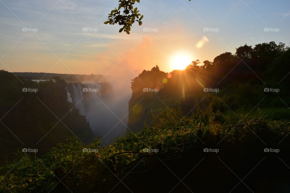 Victoria Falls sunrise, 6:00 dead quite except for the thundering water and mist, as the sun slowly touches the edges of the falls to set the mist aglow, Zimbabwe 