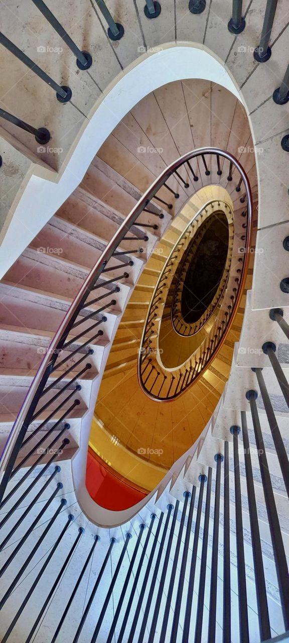 This is another one of the amazing old style buildings in the capitol of „Bavaria“, „Munich“ featuring lavish interior designs such as this narrow oval shaped spiral staircase descending downwards to the lower floors. 2022. Hypnotic Productions
