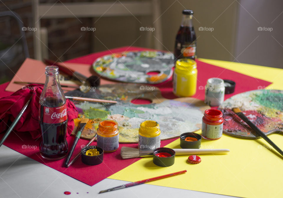 Coca-Cola bottles and colorful painting materials on the table