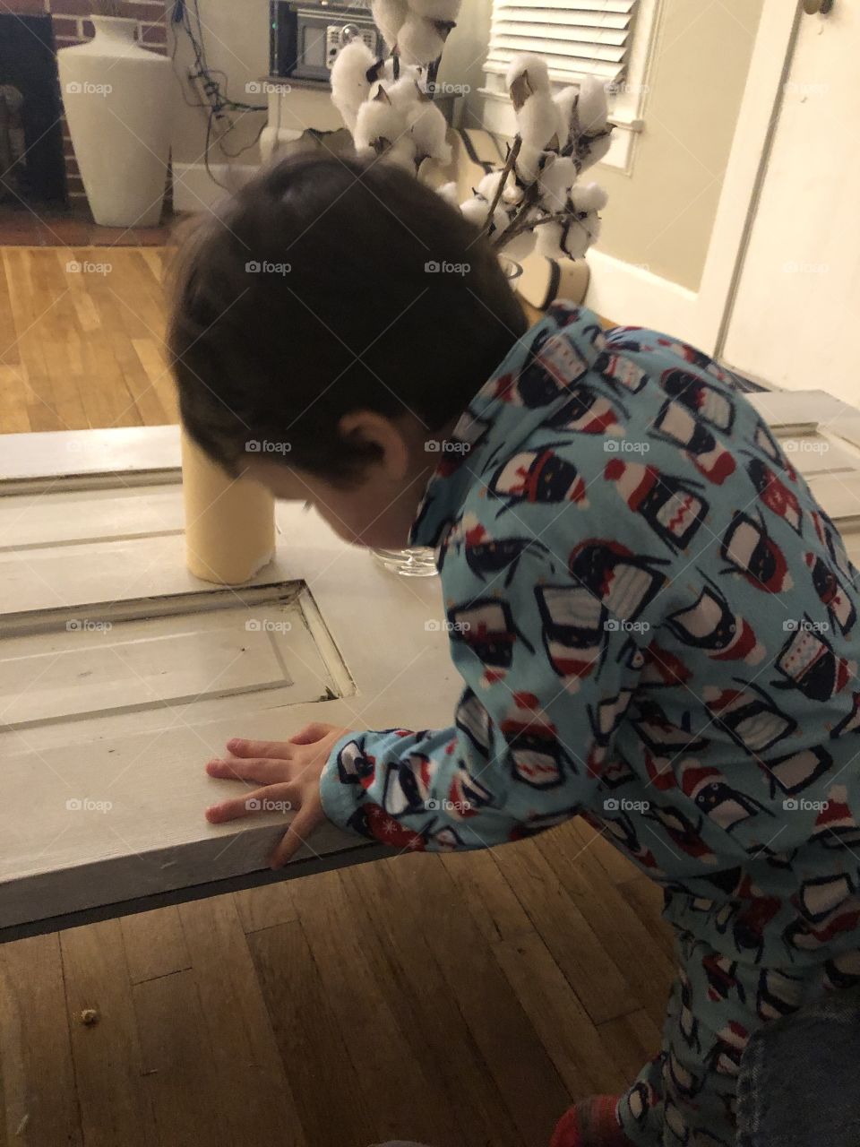 Two year old dark headed boy bending over a table too looking at something he was playing with. 