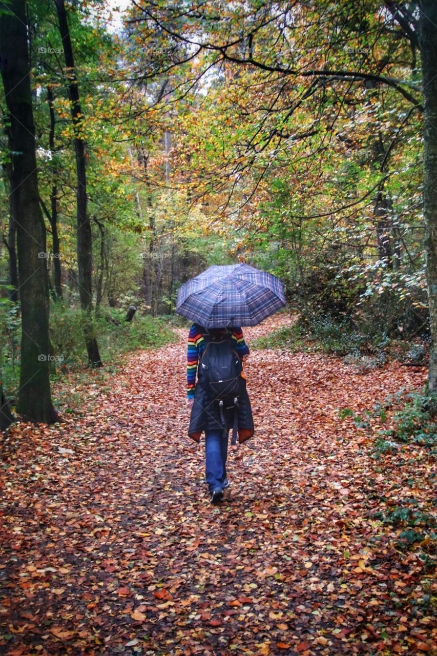 Girl with backpack and umbrella in the forest