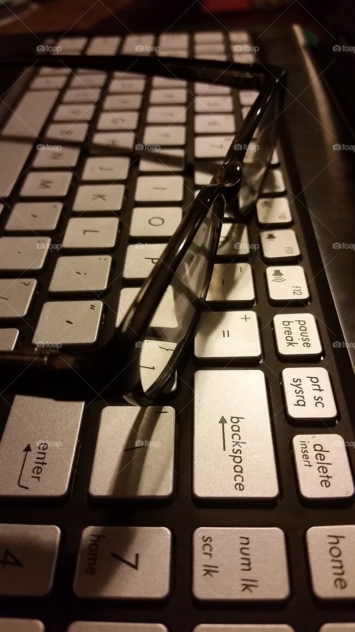 glasses perched on the keyboard of a laptop computer