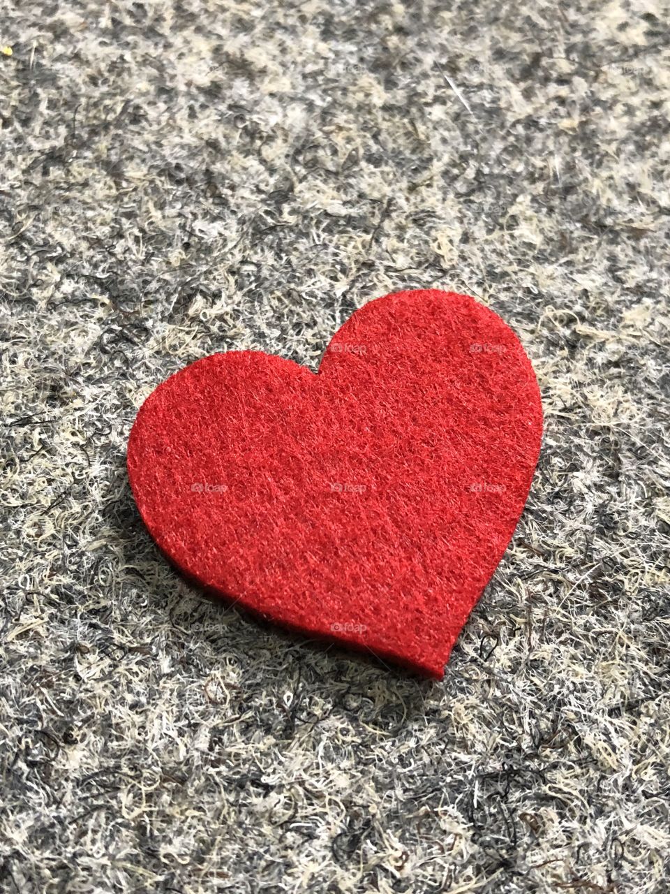Single red felt heart on grey background