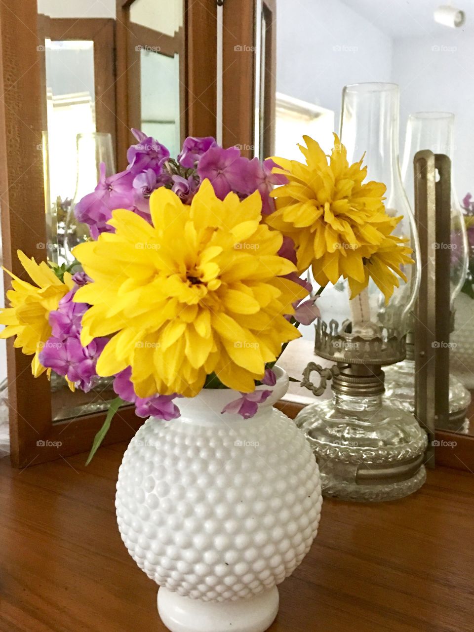 Yellow and pink flowers in vintage hobnail milk glass vase on table indoors 
