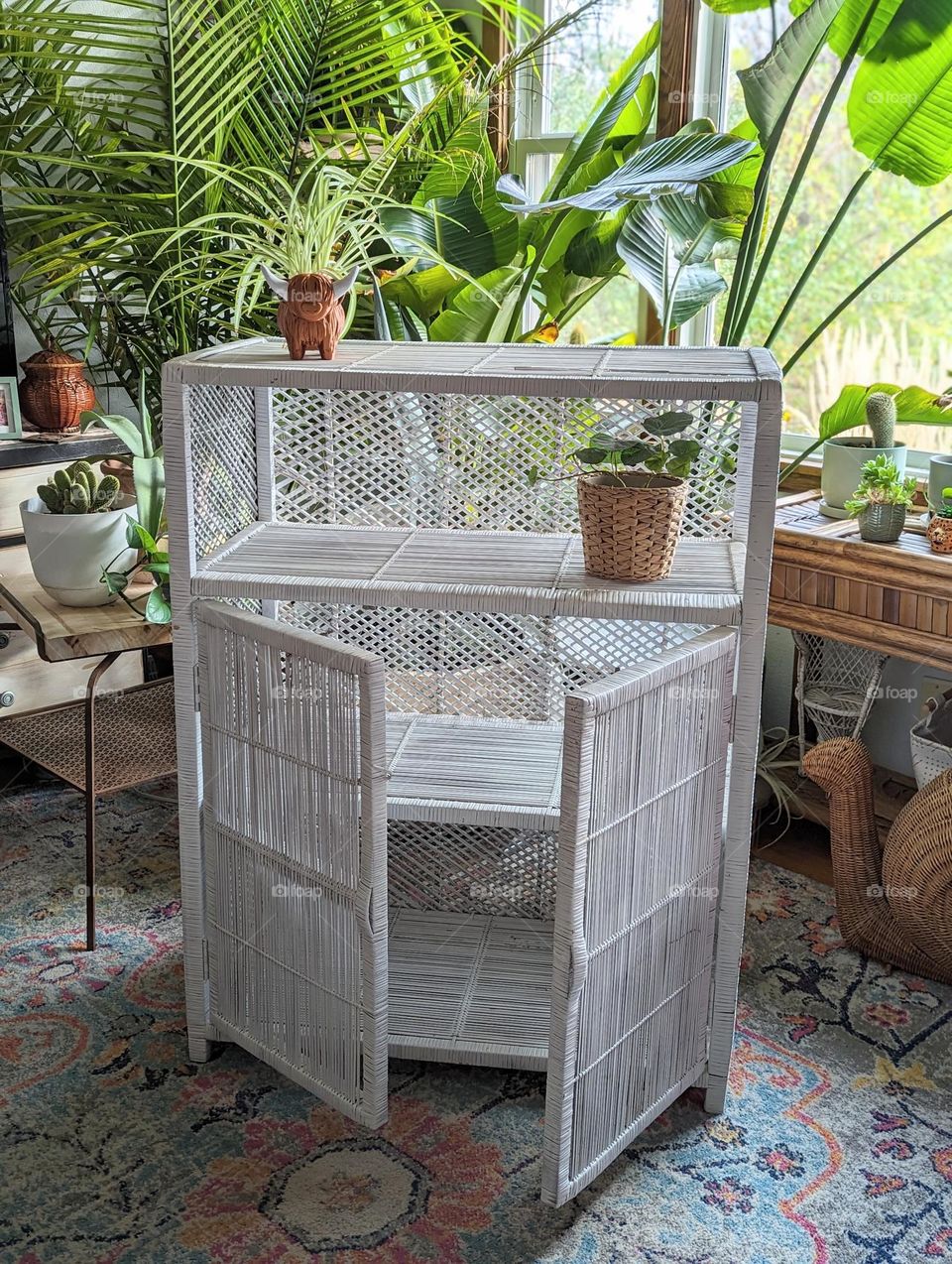 room decor white wicker shelf in a jungle living room filled with plants, vintage wicker, highlander cow planter, wicker snail, fresh green indoor plants,