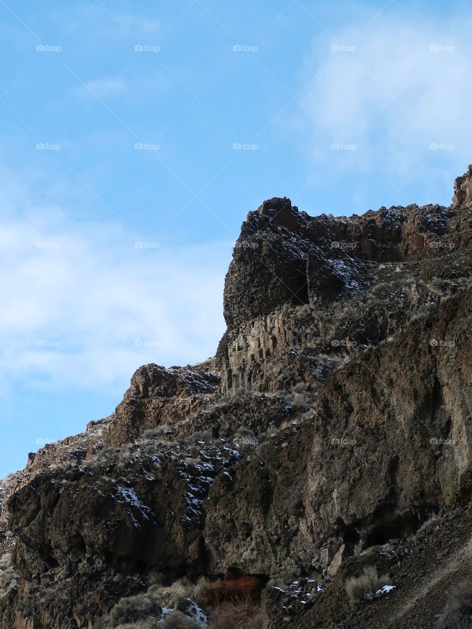 Cliffs of basalt stick out with just a bit of snow on the ground on a beautiful sunny winter day in Central Oregon. 