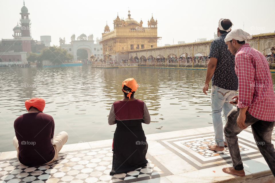 Golden temple (Harmandir Sahib Darbar Gurudwara), Amritsar, India May 2019 - Unidentifiable Punjabi Sikh pilgrim devotee "Nihang Warrior" meditating in front of holi lake of Golden Temple.