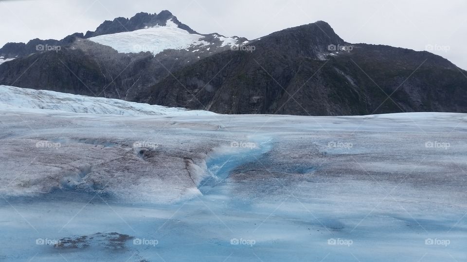 On top of Glacier in Alaska, an excursion in Juneau, blue and white ice with mountains behind