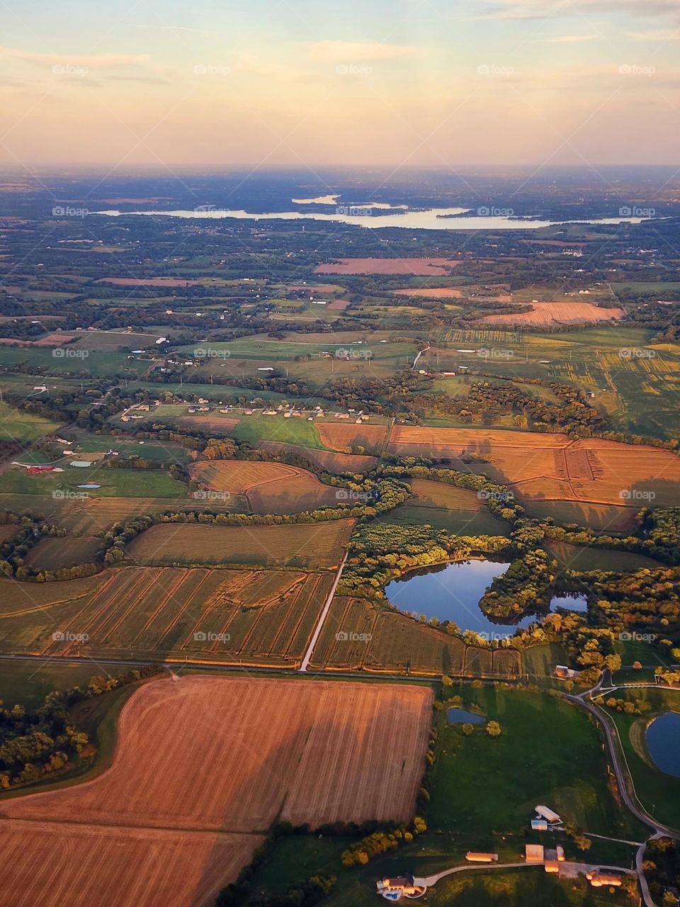 Sunset over the Central Midwest of the United States with several farms and fields apparent
