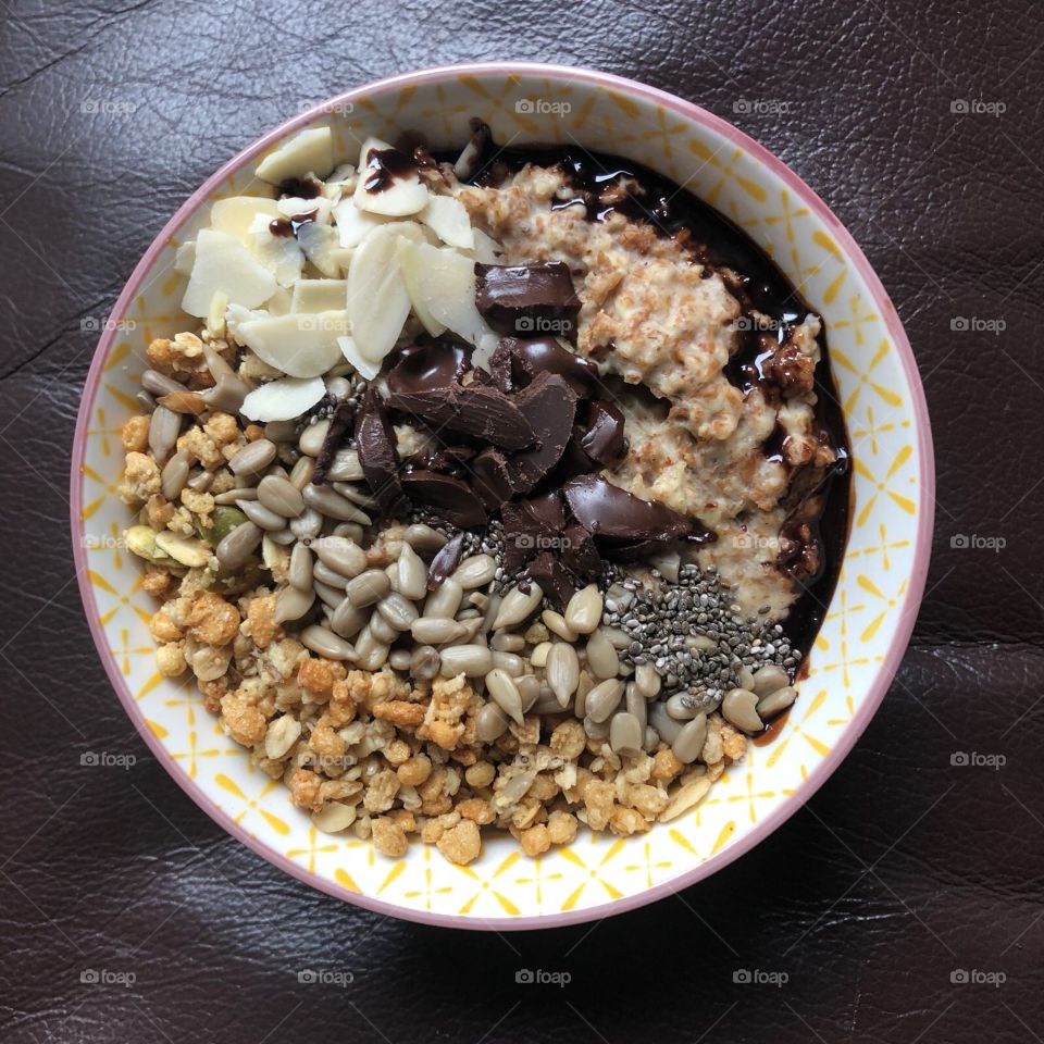 Oatmeal breakfast bowl with granola chocolate almonds and seeds 