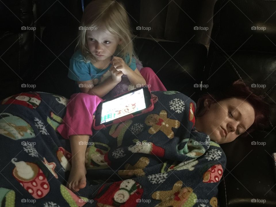 Little sister sitting on older sleeping sister