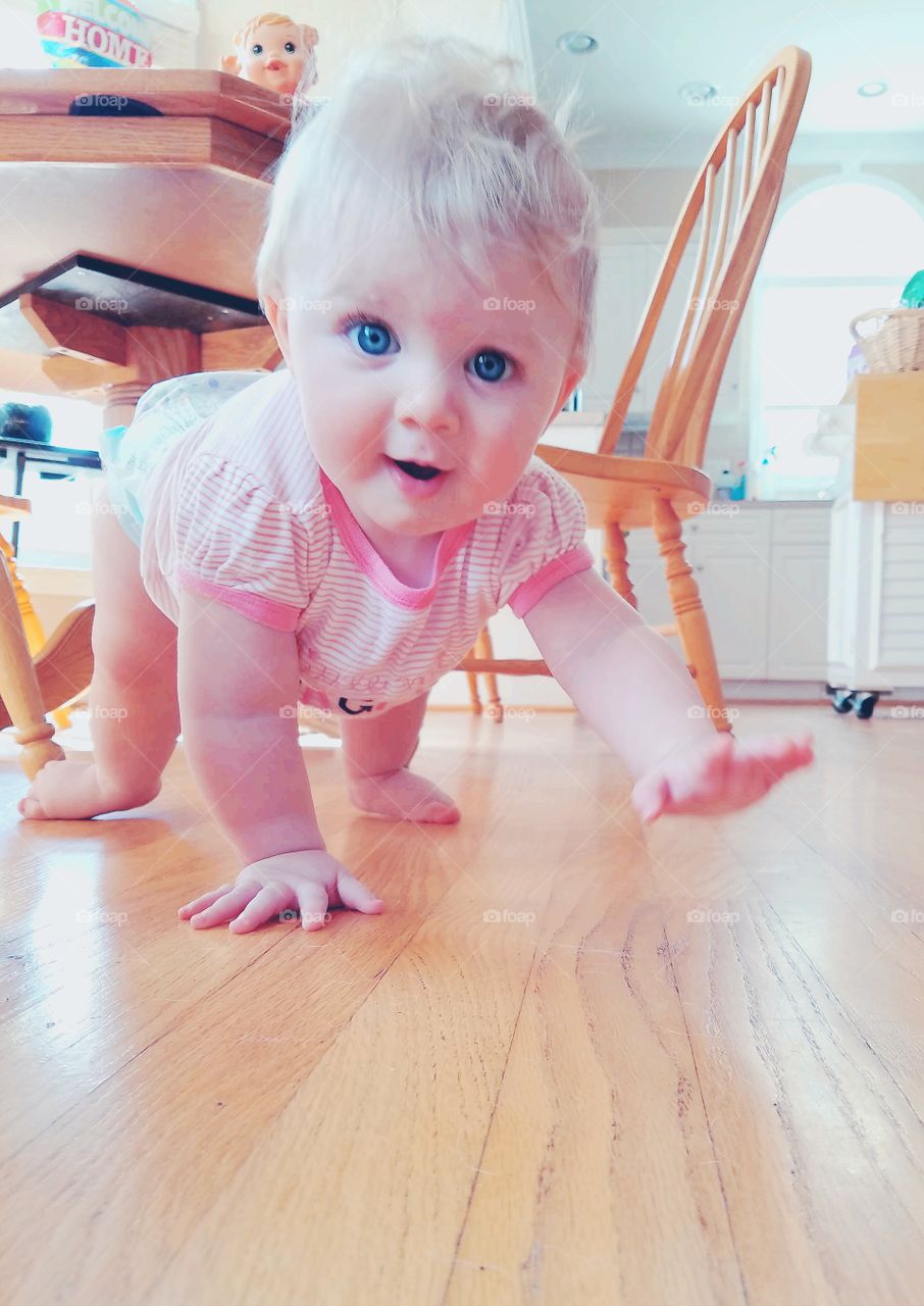 View of baby crawling on wooden floor