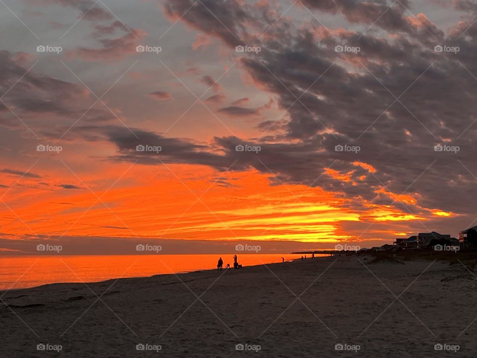 Vibrant red and orange sunset sky and clouds on a beach