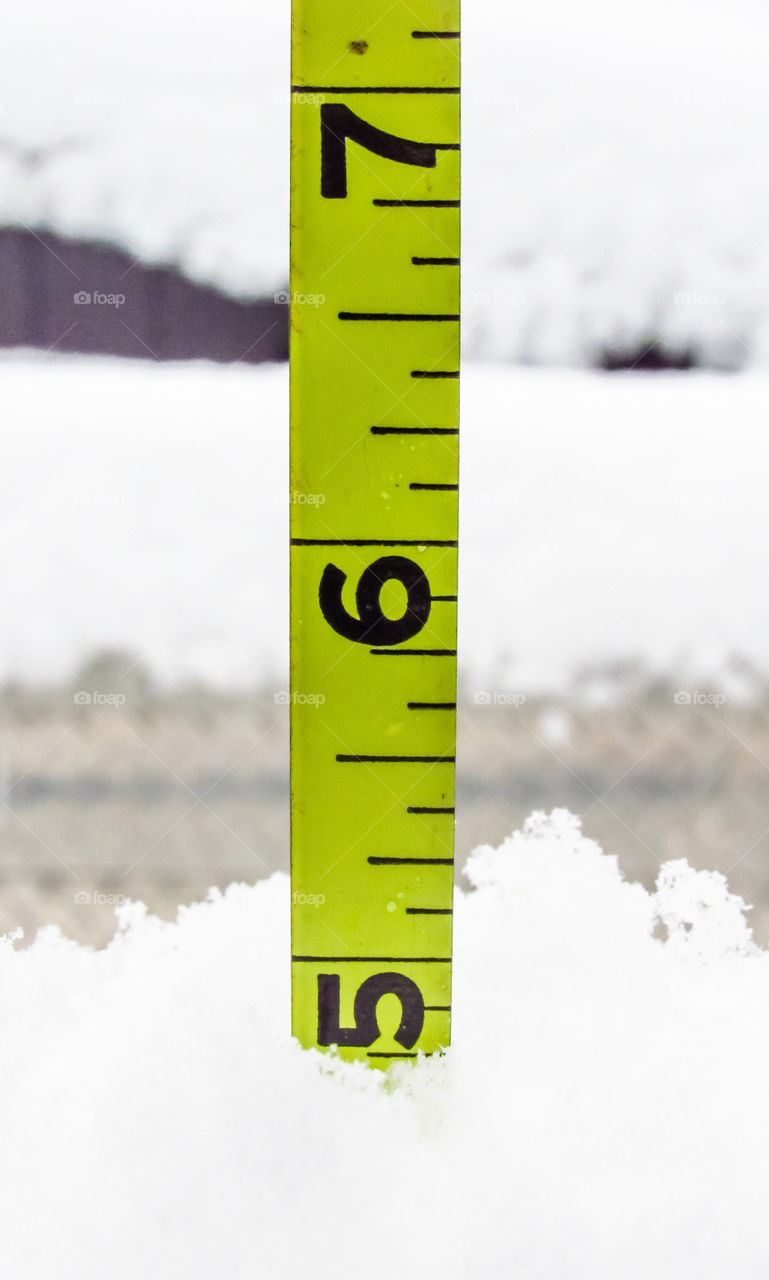 yellow tape measure measuring amount of snow fall