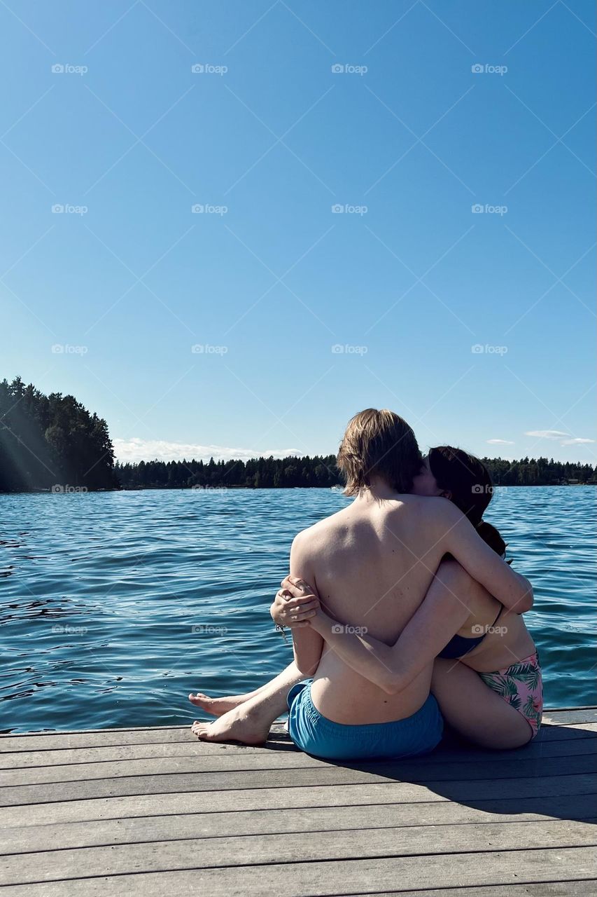 A young couple embrace on a lakeside dock during the warm summer days in Washington State