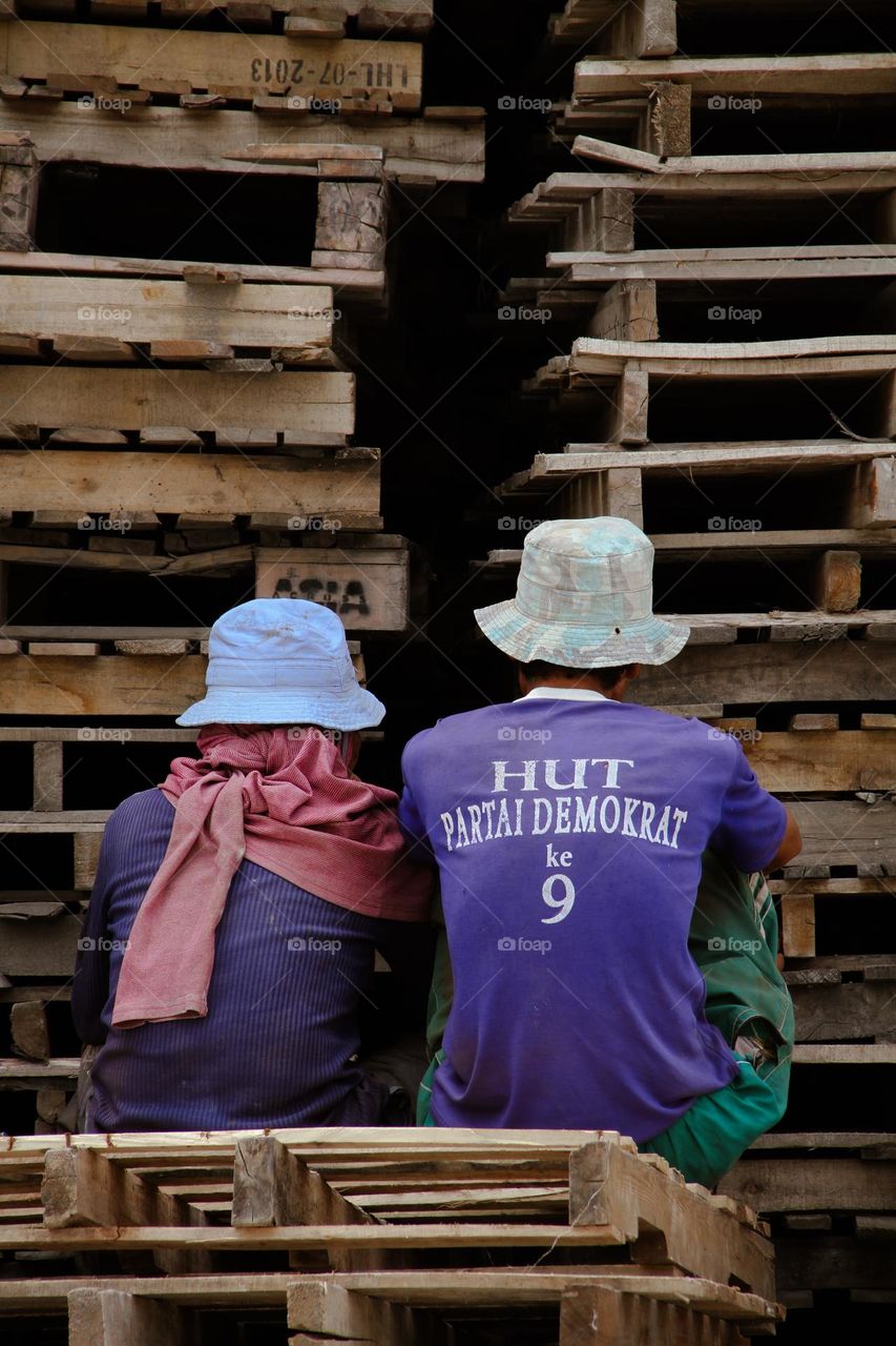 Workers taking a relaxing break behind pallets during their work in Sunda Kelapa harbour, Jakarta, Indonesia.