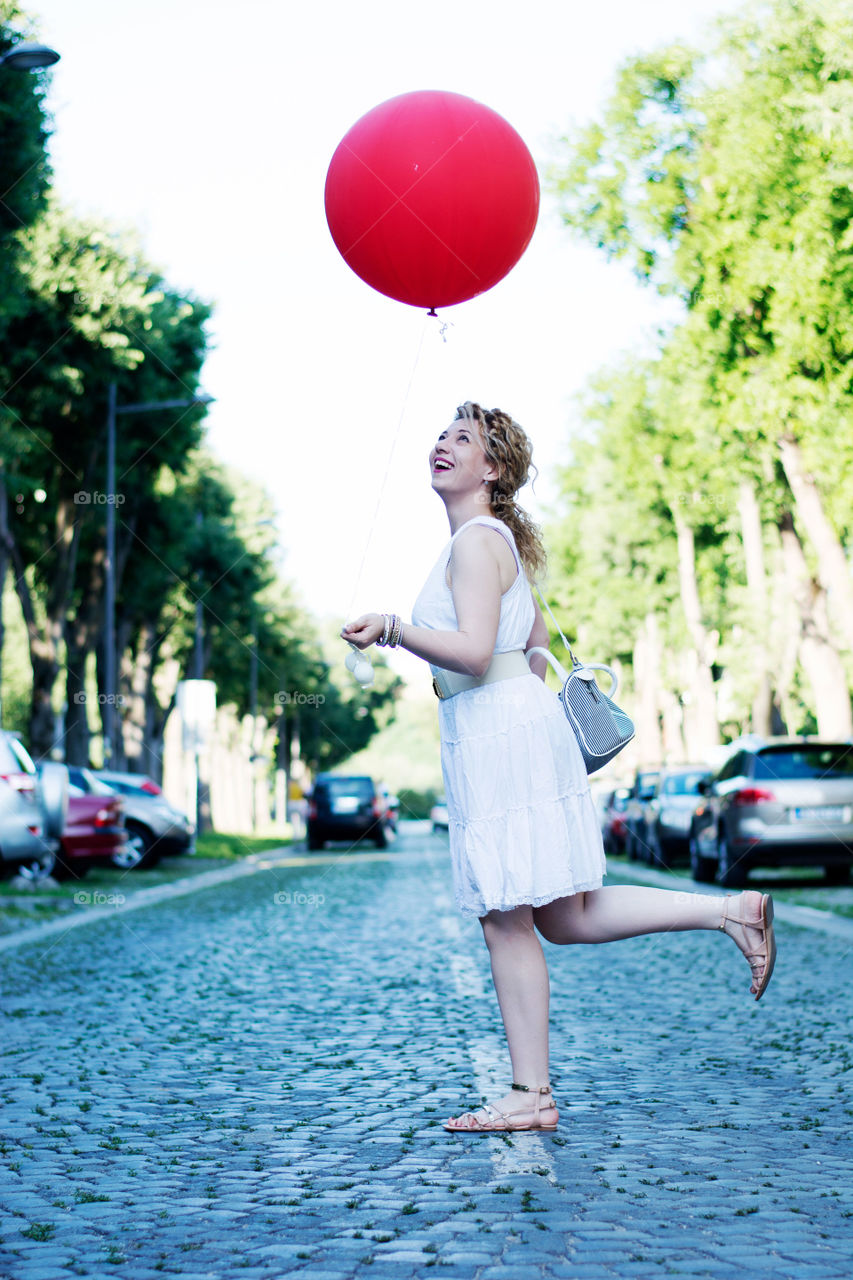 girl with big red ballon. curly blond girl with big red ballon crossing the street