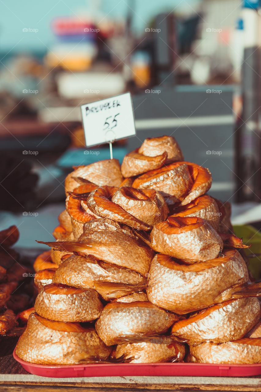 Closeup of stack of fresh smoked fishes at the market over a sea