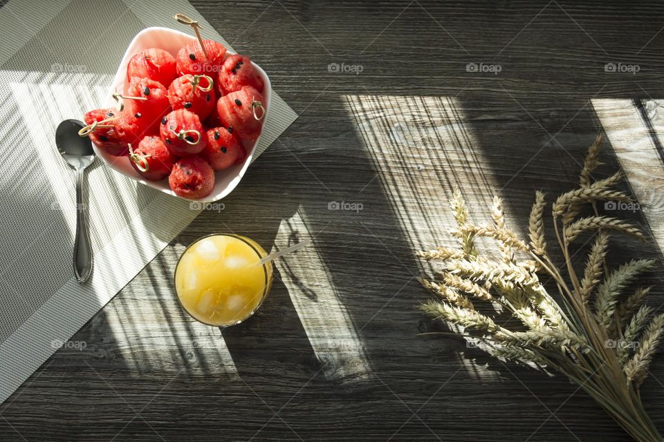 light summer snacks in the form of a watermelon and a glass of freshly squeezed orange juice on a wooden table