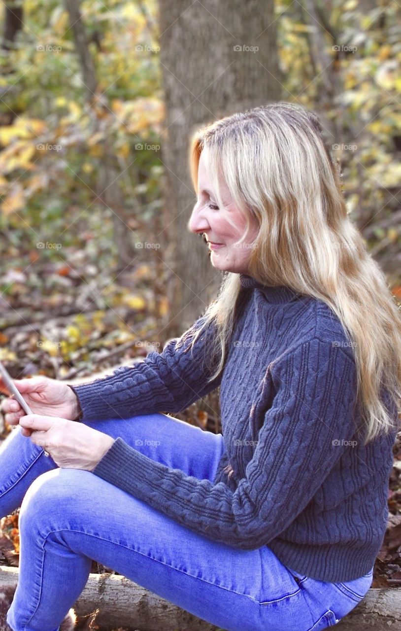 Woman sitting outside reading her phone 